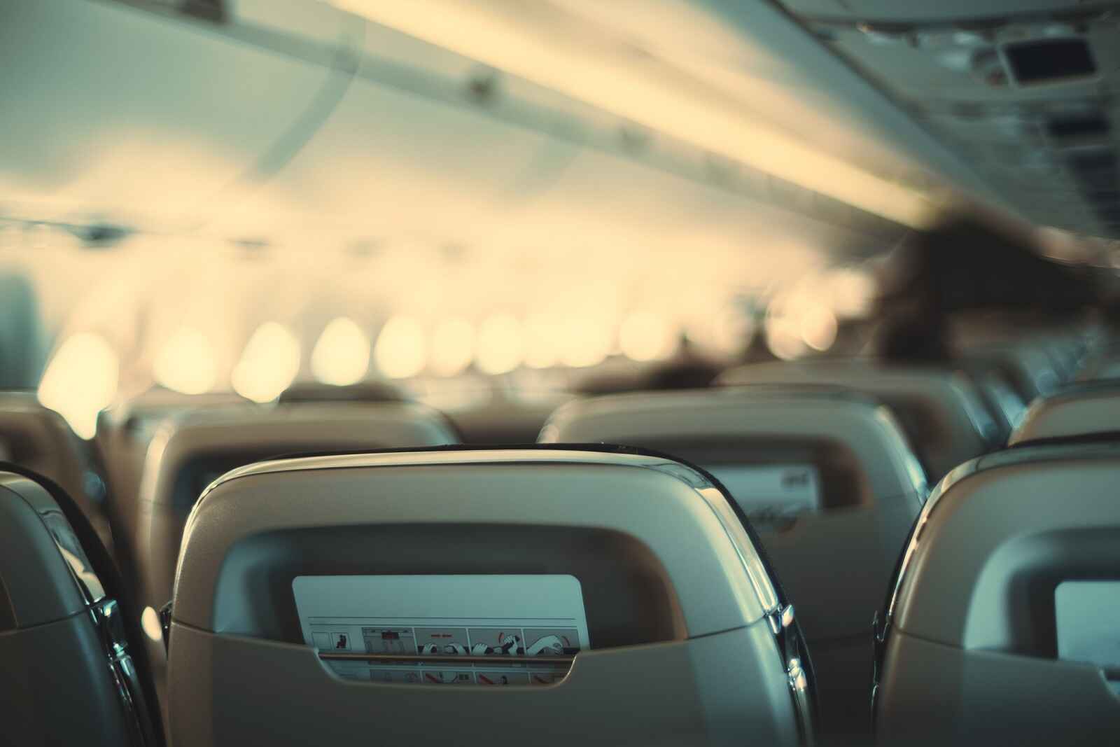 A blurred image of airplane seating from behind rows of passenger chairs