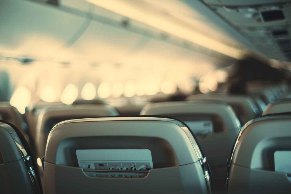 A blurred image of airplane seating from behind rows of passenger chairs