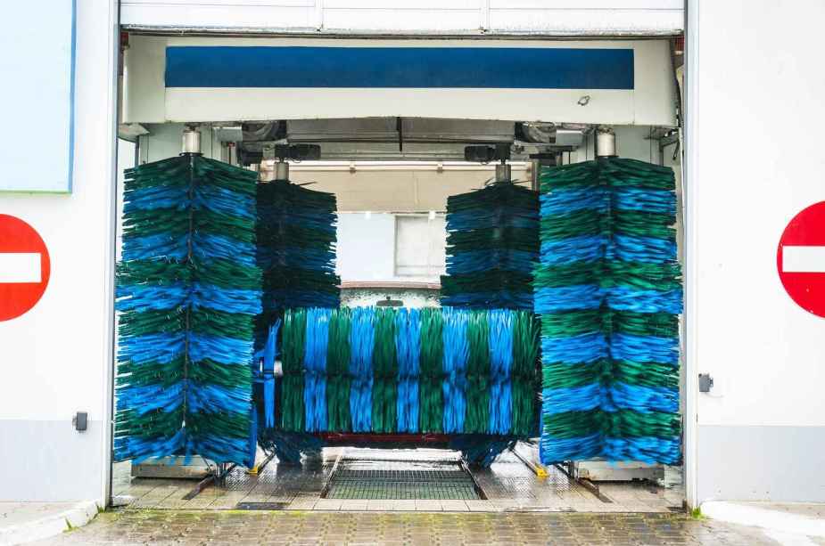 Blue and green-striped car wash bushes are shown in a car wash bay
