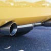 A yellow car's rear bumper shows dual exhaust tips close to the road