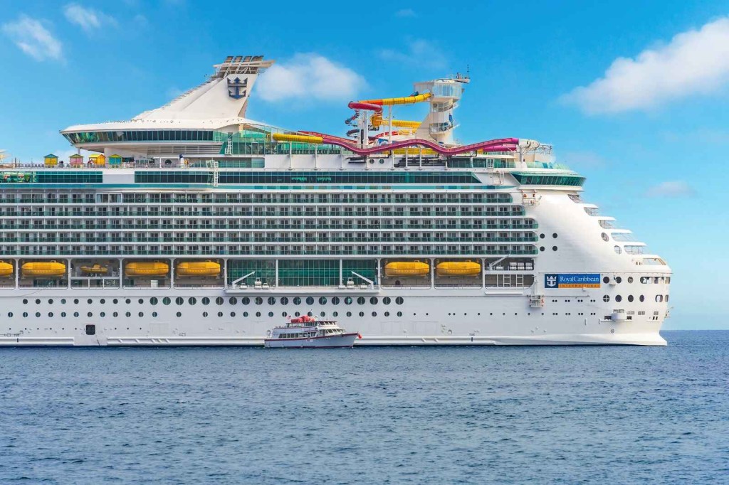 A Royal Caribbean cruise ship in profile view with water park on upper deck
