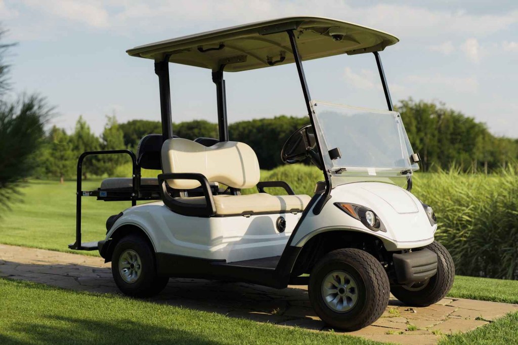 A white golf cart parked at a golf course