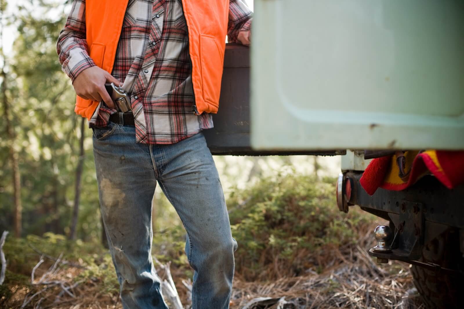 A man with a revolver and his truck. 