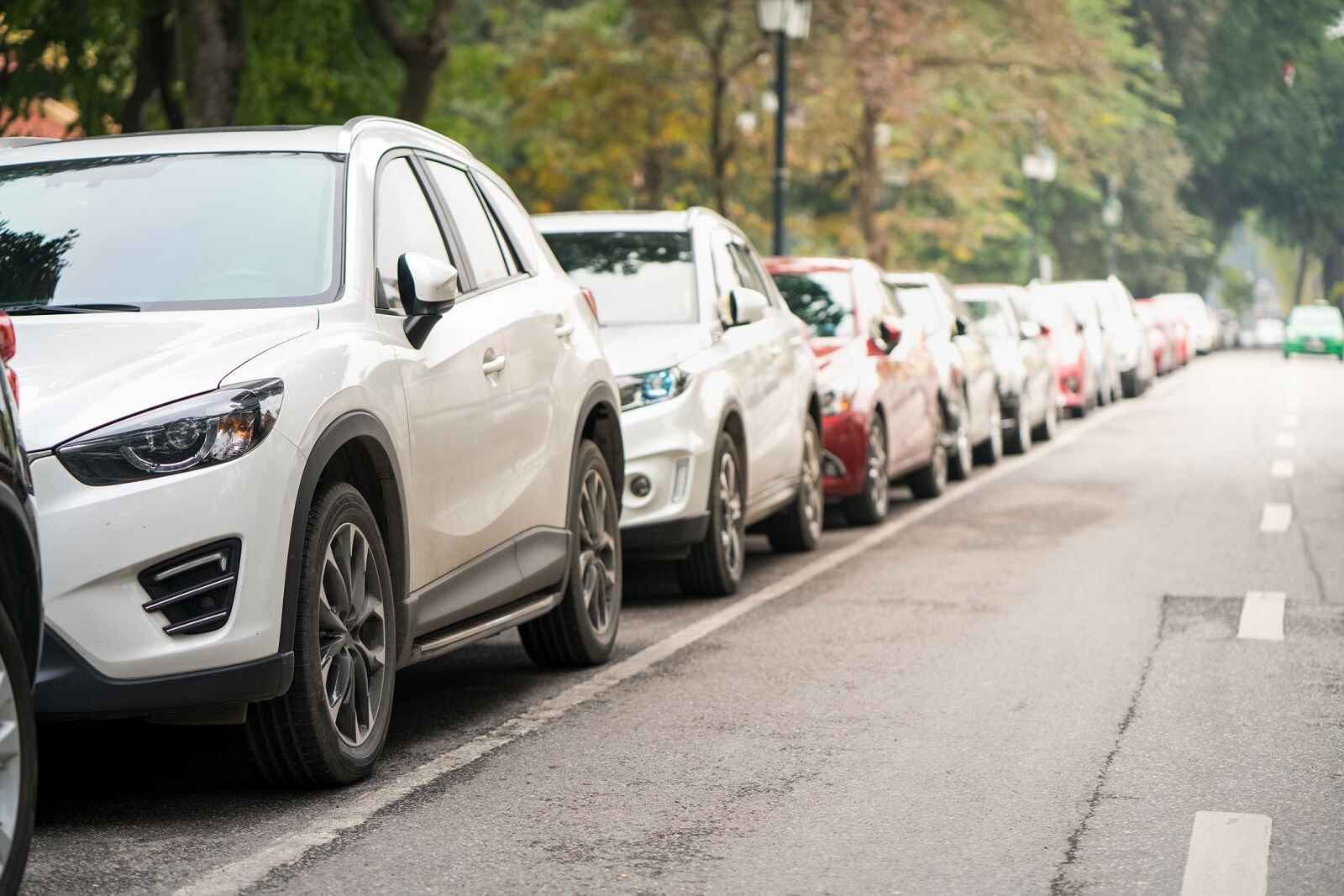 A row of SUVs parallel parked on a city street