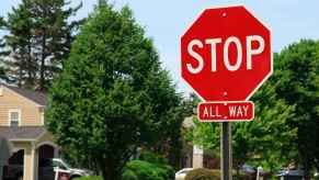 A red stop sign with "ALL WAY" posted under it at a residential intersection