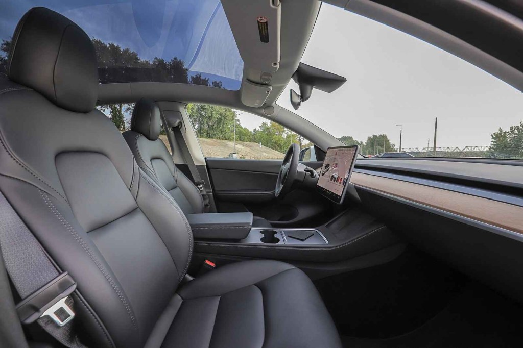 A black leather Tesla EV interior with seat belt showing
