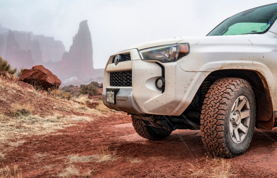 A white 2016 Toyota 4Runner parked in left front corner angle view facing left frame with Moab in background