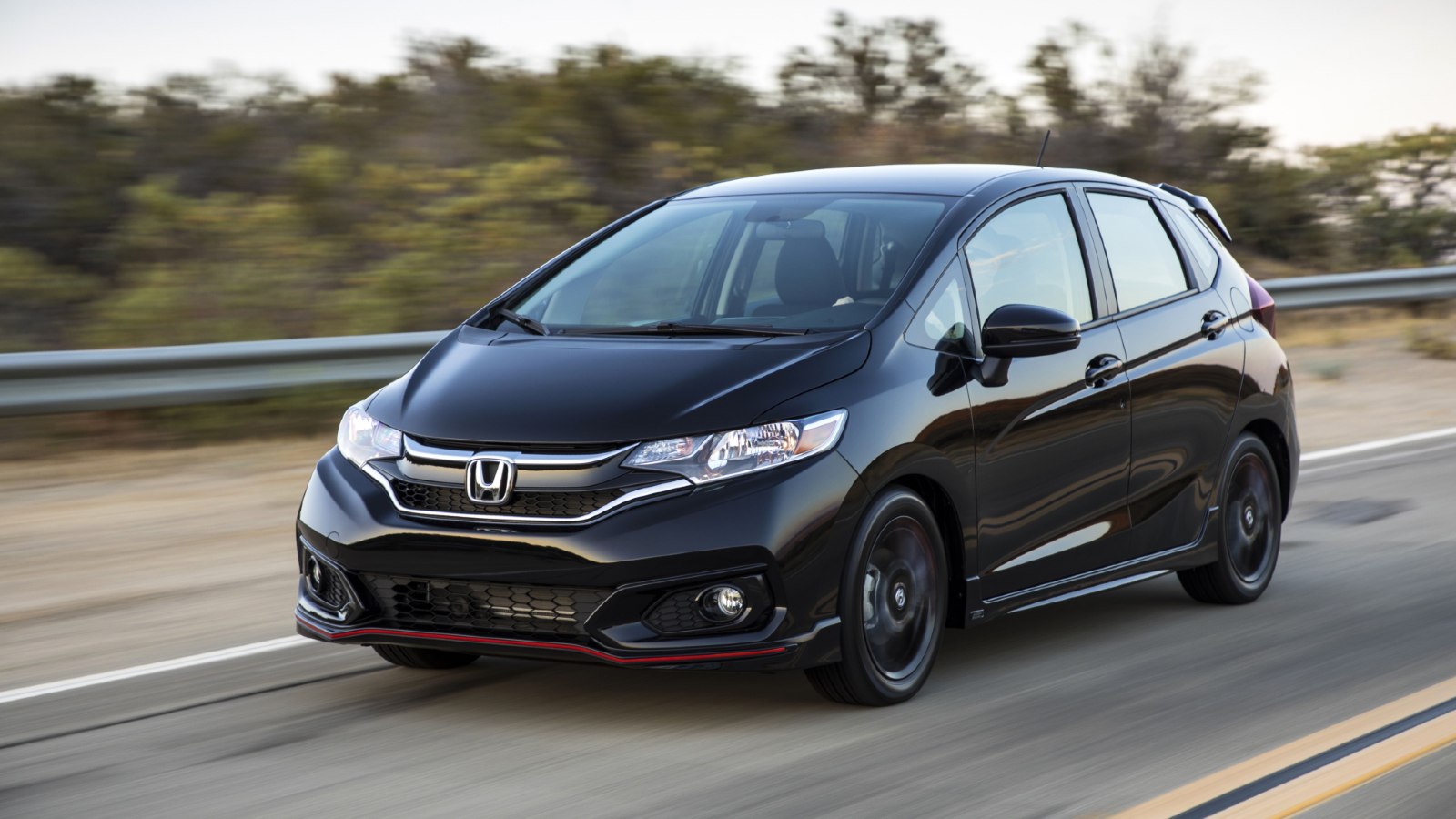 Black 2020 Honda Fit driving on a highway.