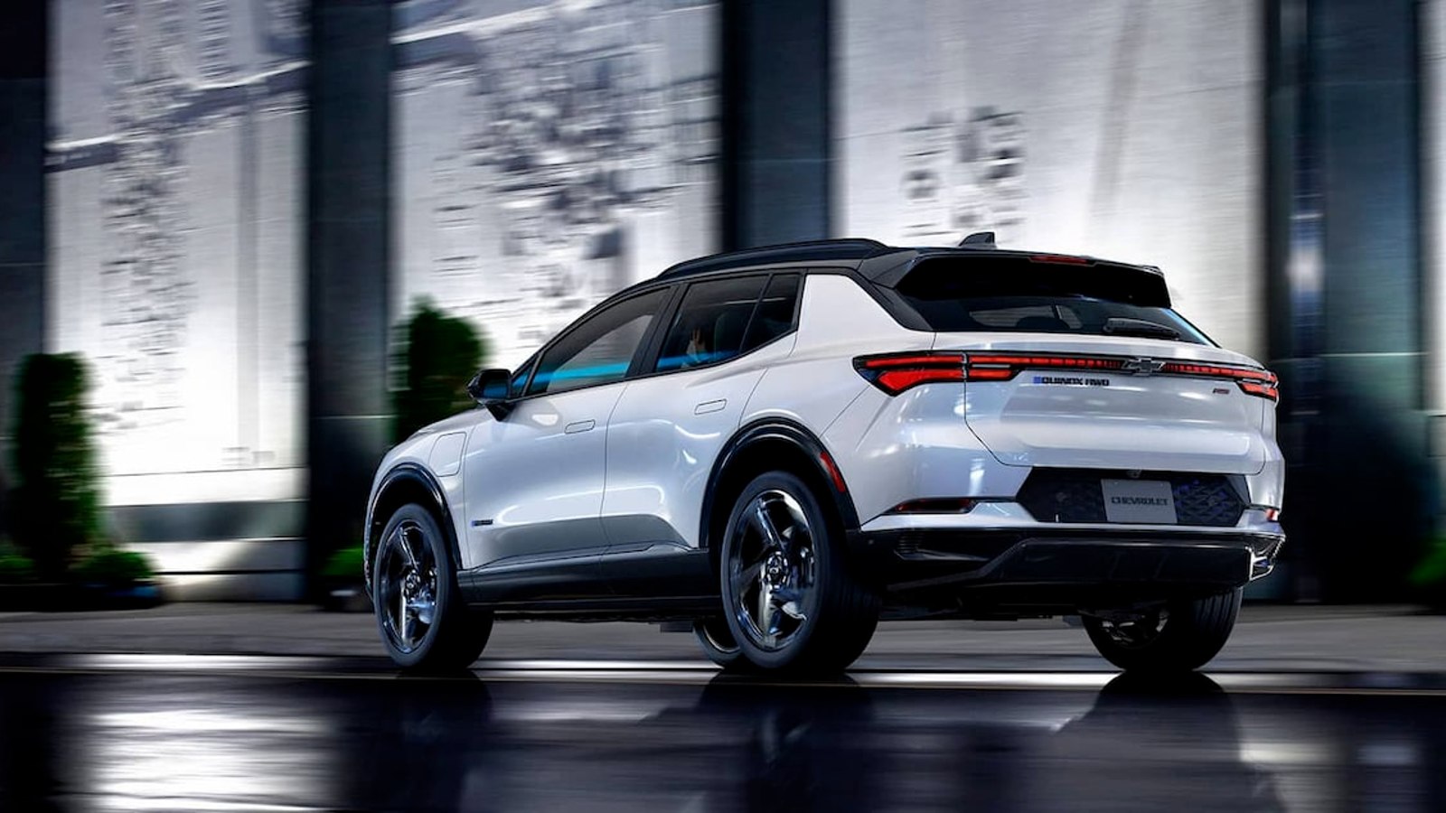 White 2024 Chevy Equinox EV driving on a road.