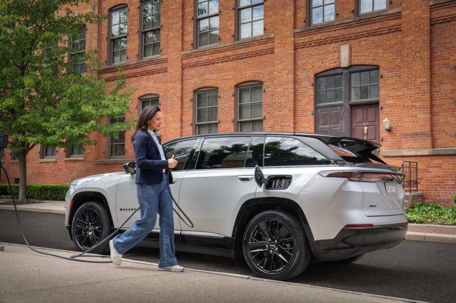 Woman walks to her Jeep EV with a charging cable.