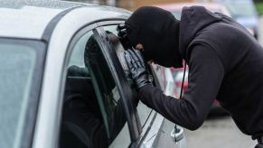 A thief peers through a hatchback's window looking for a gun in the car after noticing a gun decal.
