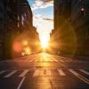 The sun rises over a city street and its standard road lane width.