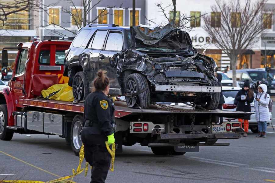 Crashed SUV with a smashed front end sitting on a rollback tow truck