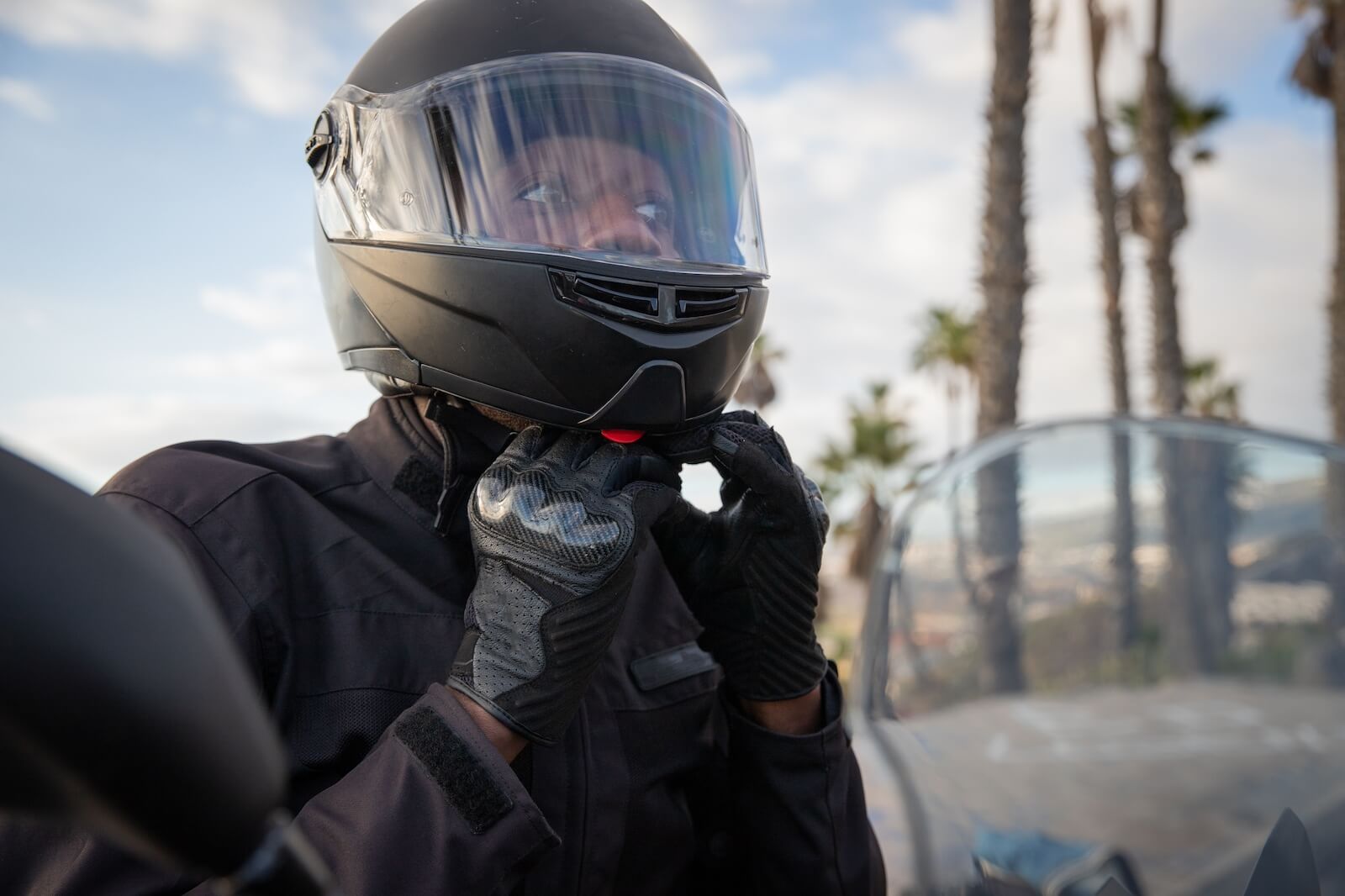 A rider puts on their DOT full-face motorcycle helmet. 