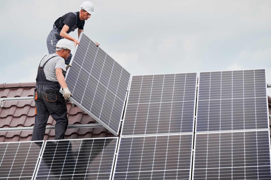 Two men on a roof install solar panels.