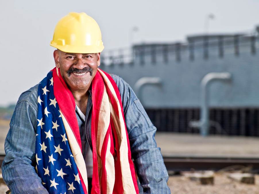 U.S. factory worker with a hard hat and wearing an American flag.