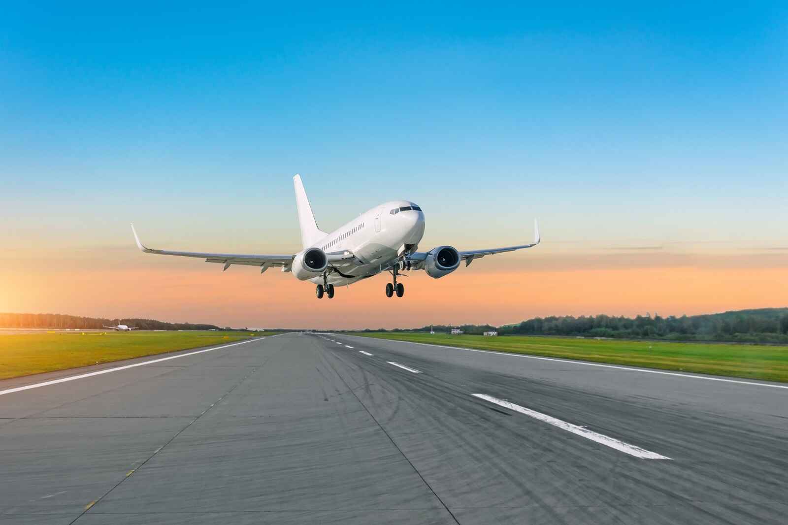 An airplane landing on a runway at sunset in right front angle view