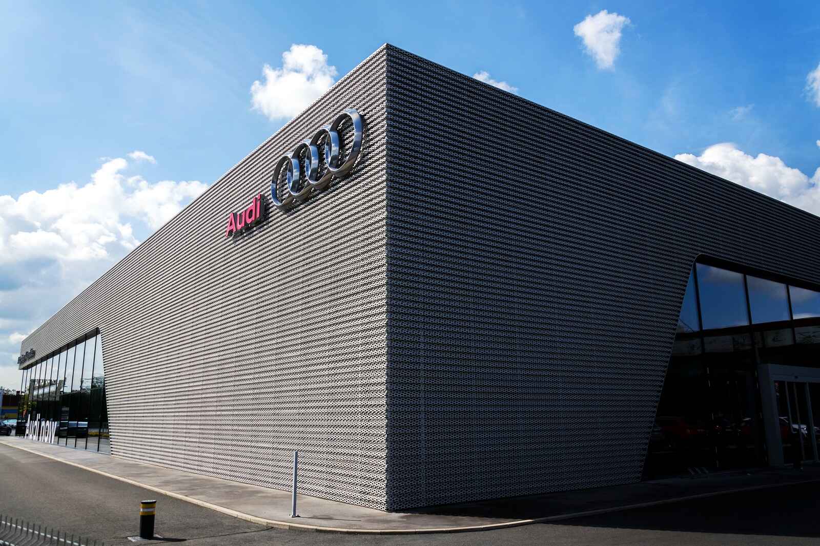 The exterior of a large Audi dealership building with Audi name and logo on upper corner