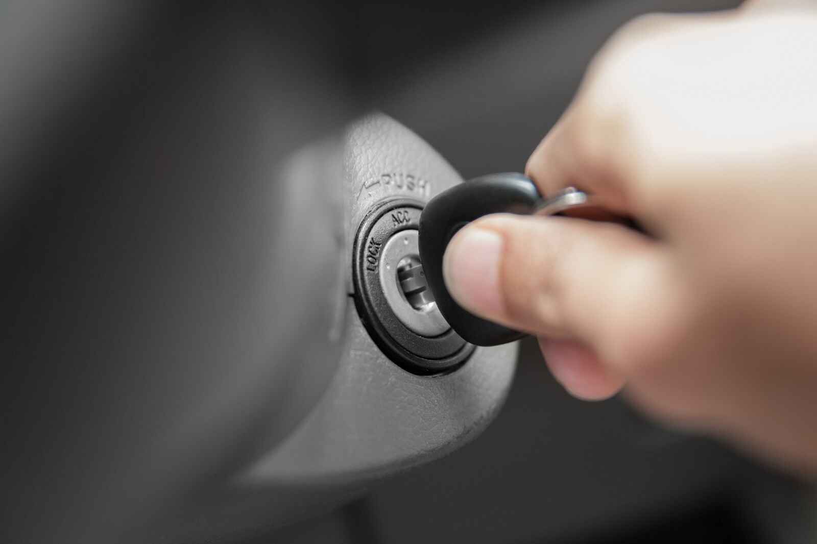 A car key is being inserted into an ignition cylinder in close view