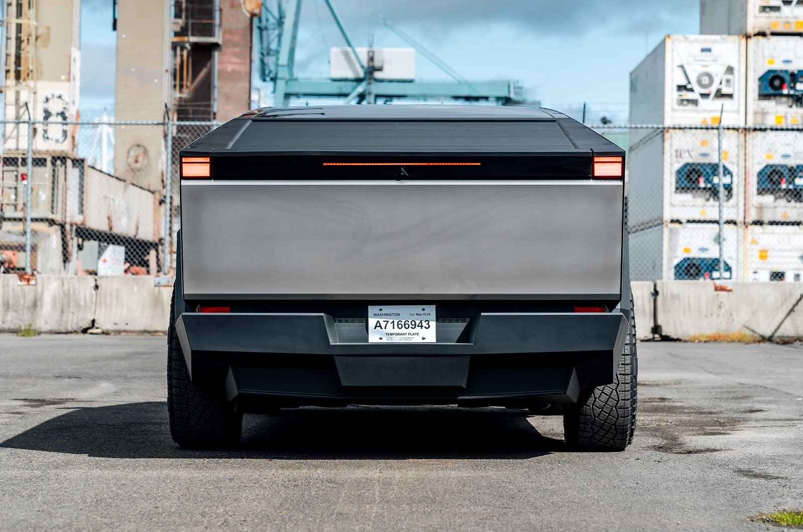 A Tesla Cybertruck at a shipping yard parked in close direct rear view