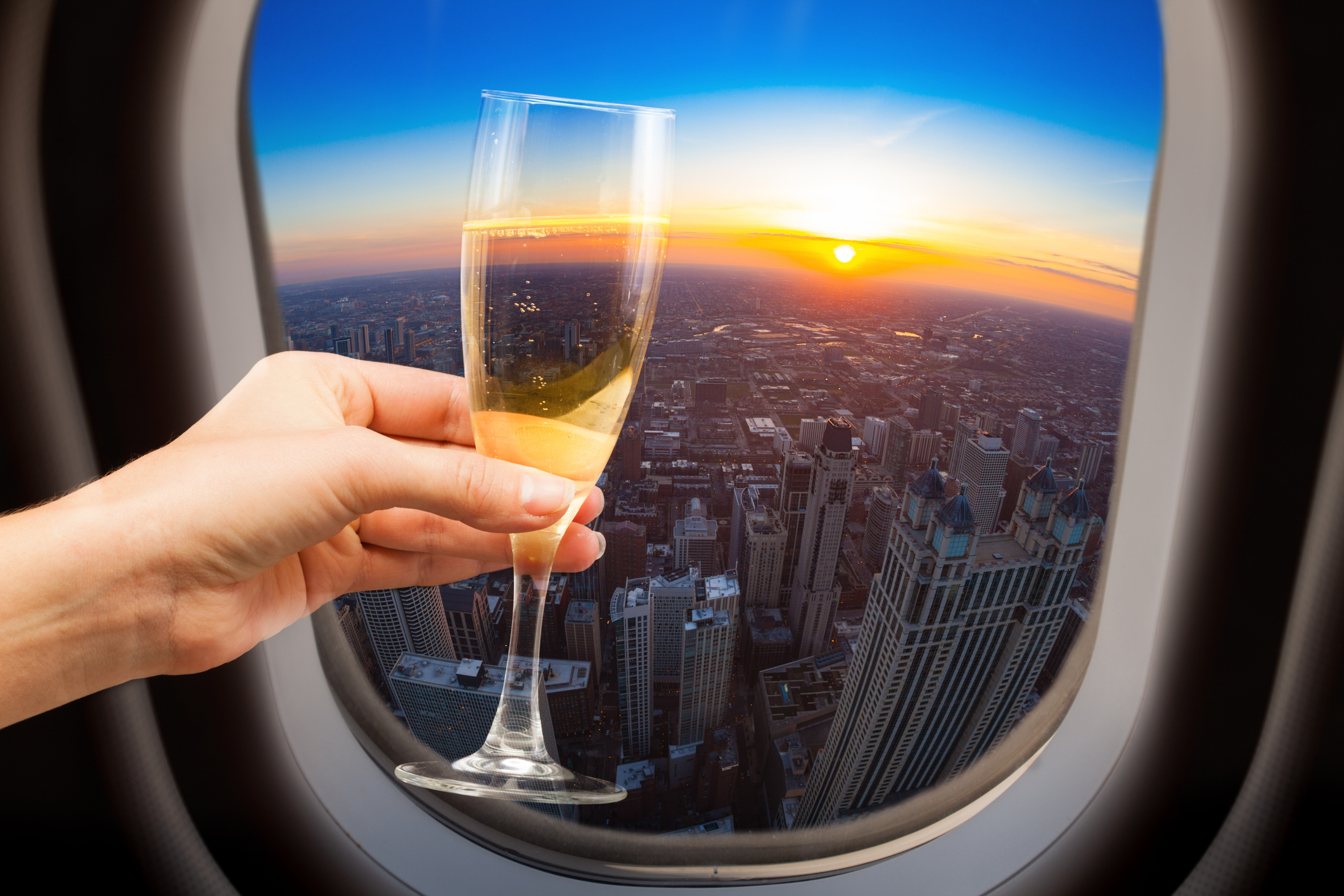 A woman holding champagne near an airplane window