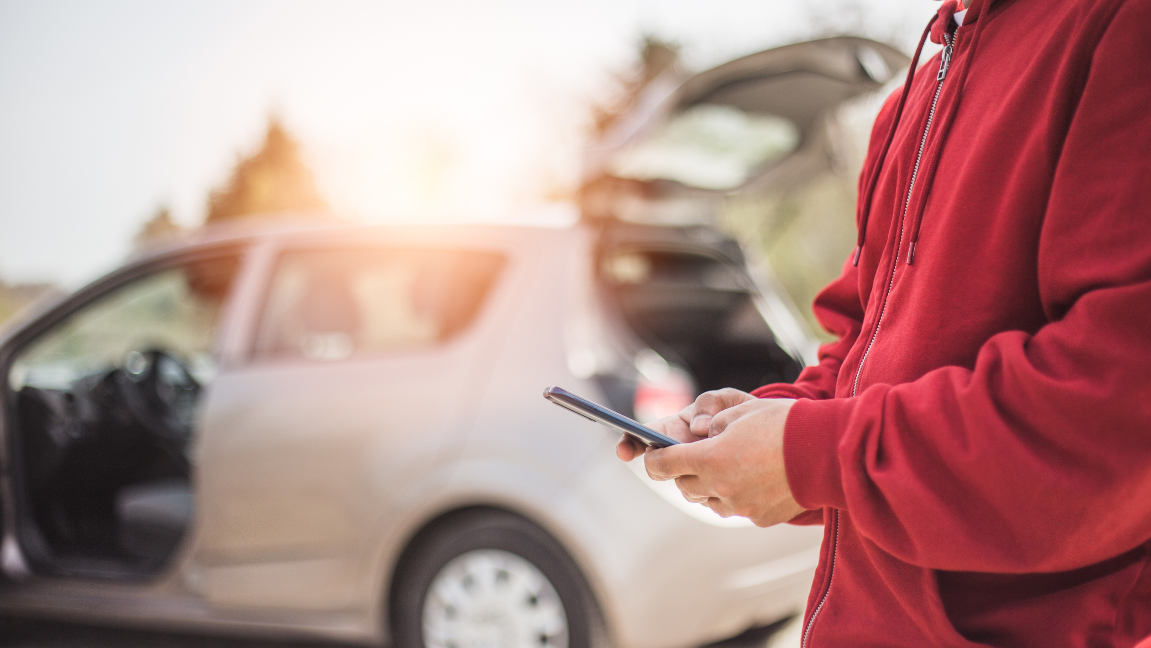 A man using his phone beside his car