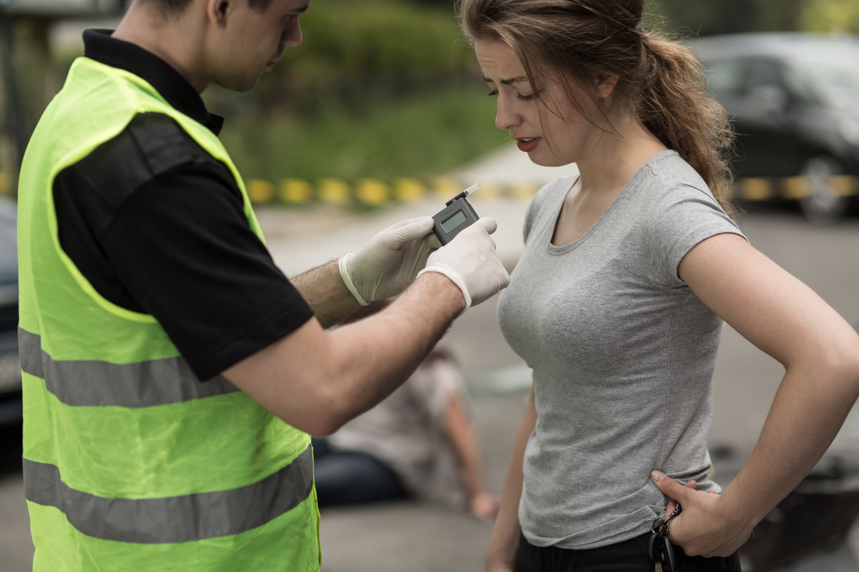 A police officer giving a woman a breathalyzer test 