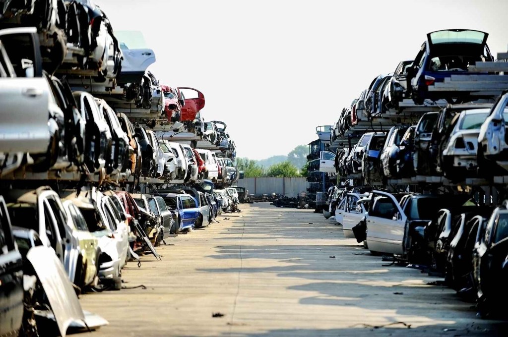 Looking down the aisle of two rows of triple-stacked junked cars at a scrapyard