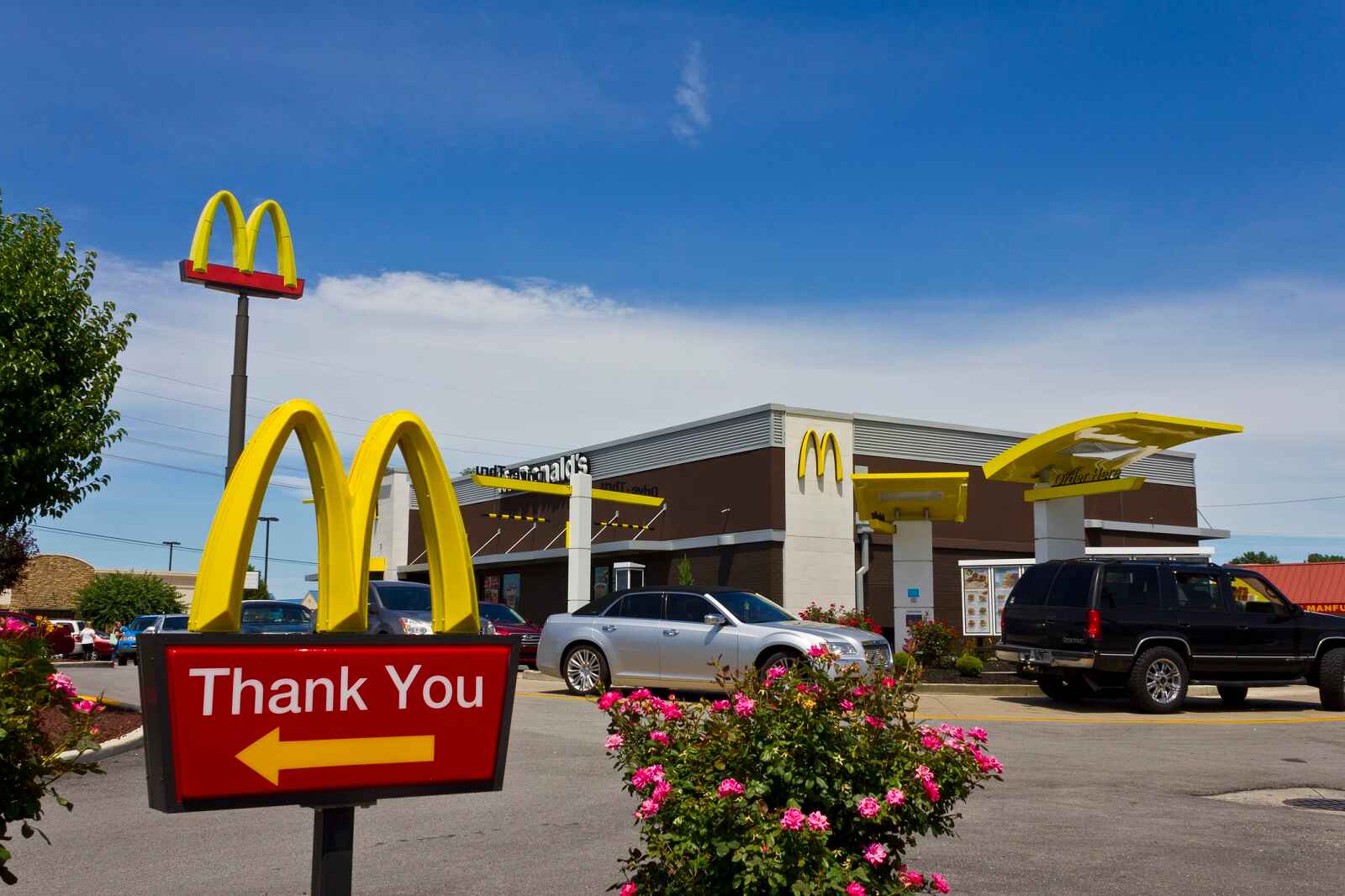 A McDonald's restaurant exterior with cars in drive-thru lane