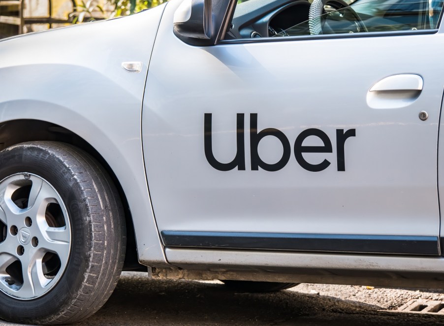 A close view of a white car with black Uber logo lettering on left front door