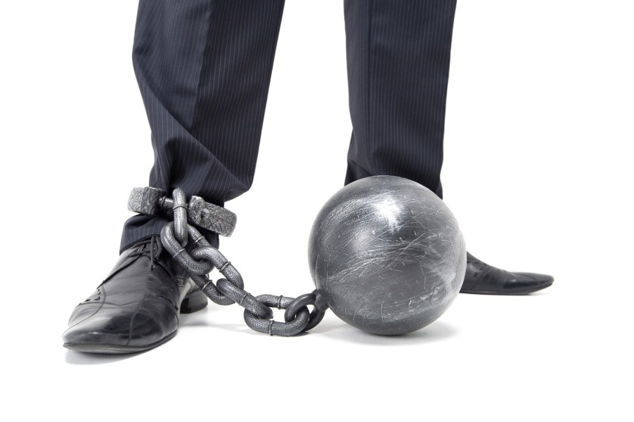 Man in nice pants and shoes drags along a ball-and-chain
