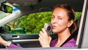 Woman uses a breathalyzer attached to her car.