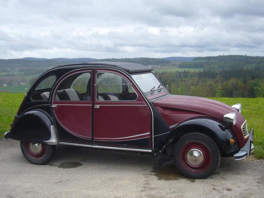 Red and black Citroen 2CV parked on a mountaintop.