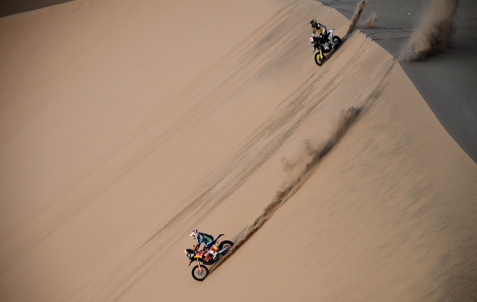 KTM off-road motorycle and austrian rider competing in the Dakar rally atop a sand dune
