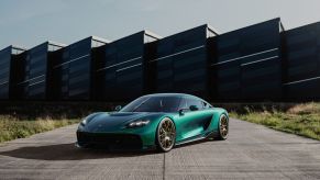 Green Koenigsegg Gemera Hyper-GT car parked in front of a futuristic building.