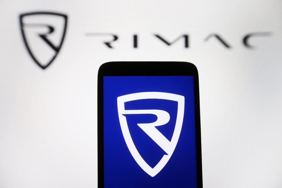 The Rimac logo on a cellphone in front of a Rimac sign.