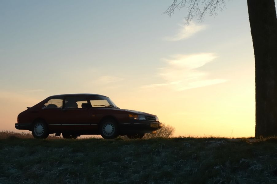 A Saab 900 Turbo shows off its merit among sports cars at sunset.