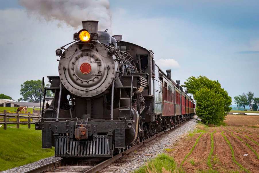 Restored classic steam locomotive on train tracks in the country.