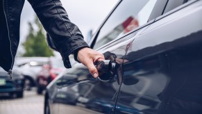 A man's hand on a car door handle opening it as a car theft example using the "Game Boy" key emulator theft device