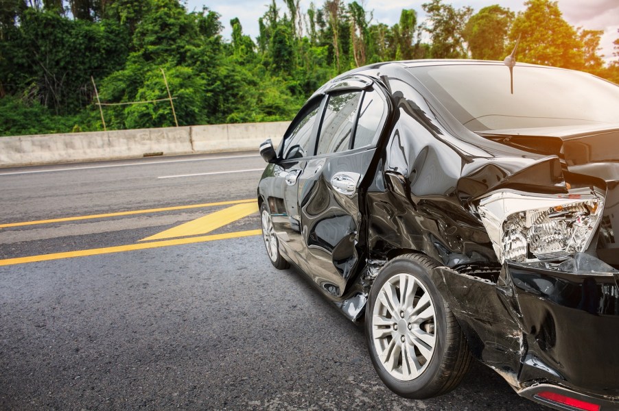Black car in left rear angle smashed down the side after a car accident likely total loss Progressive insurance settled a total loss value underpayment lawsuit in July 2024
