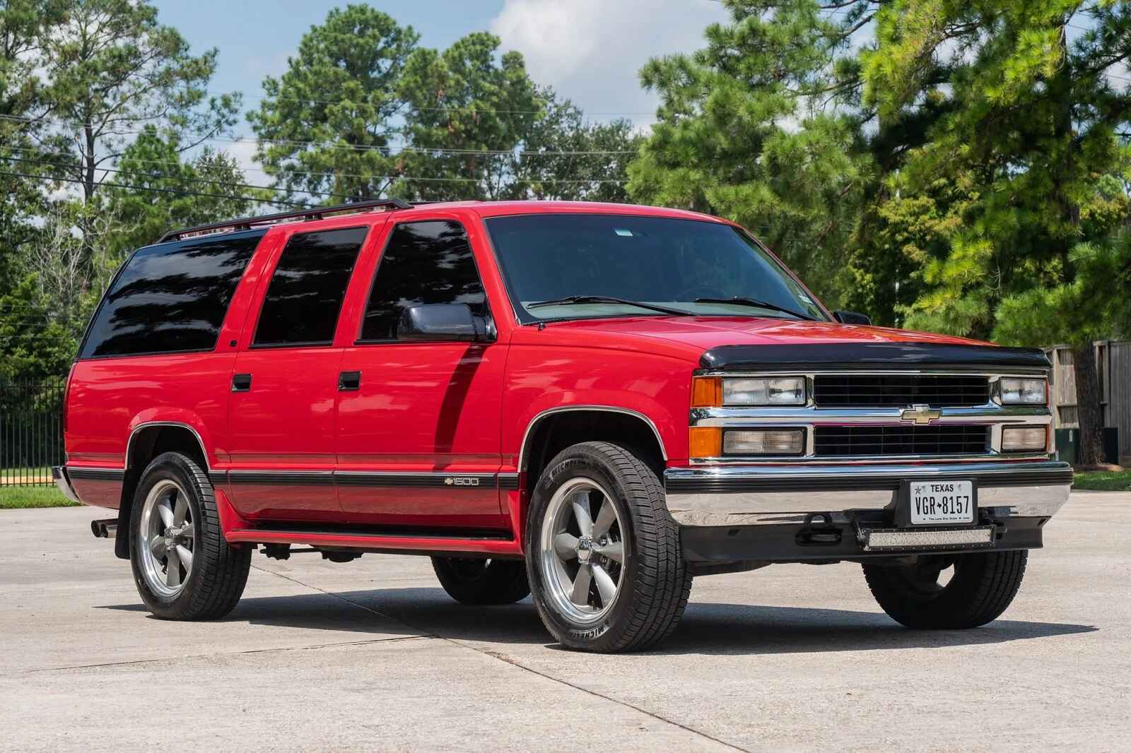 A red 1999 Chevy Suburban SUV parked in right front view