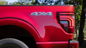 The 4x4 badge on the bed of a red Ford F-150 pickup truck.