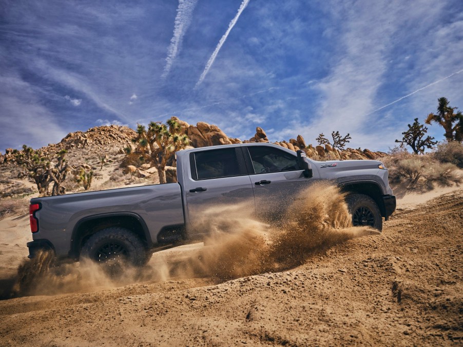 2024 Chevrolet Silverado HD ZR2pickup truck in full right profile view kicking up dust Chevrolet is owned by GM which is beating Ford for overall truck sales in 2024