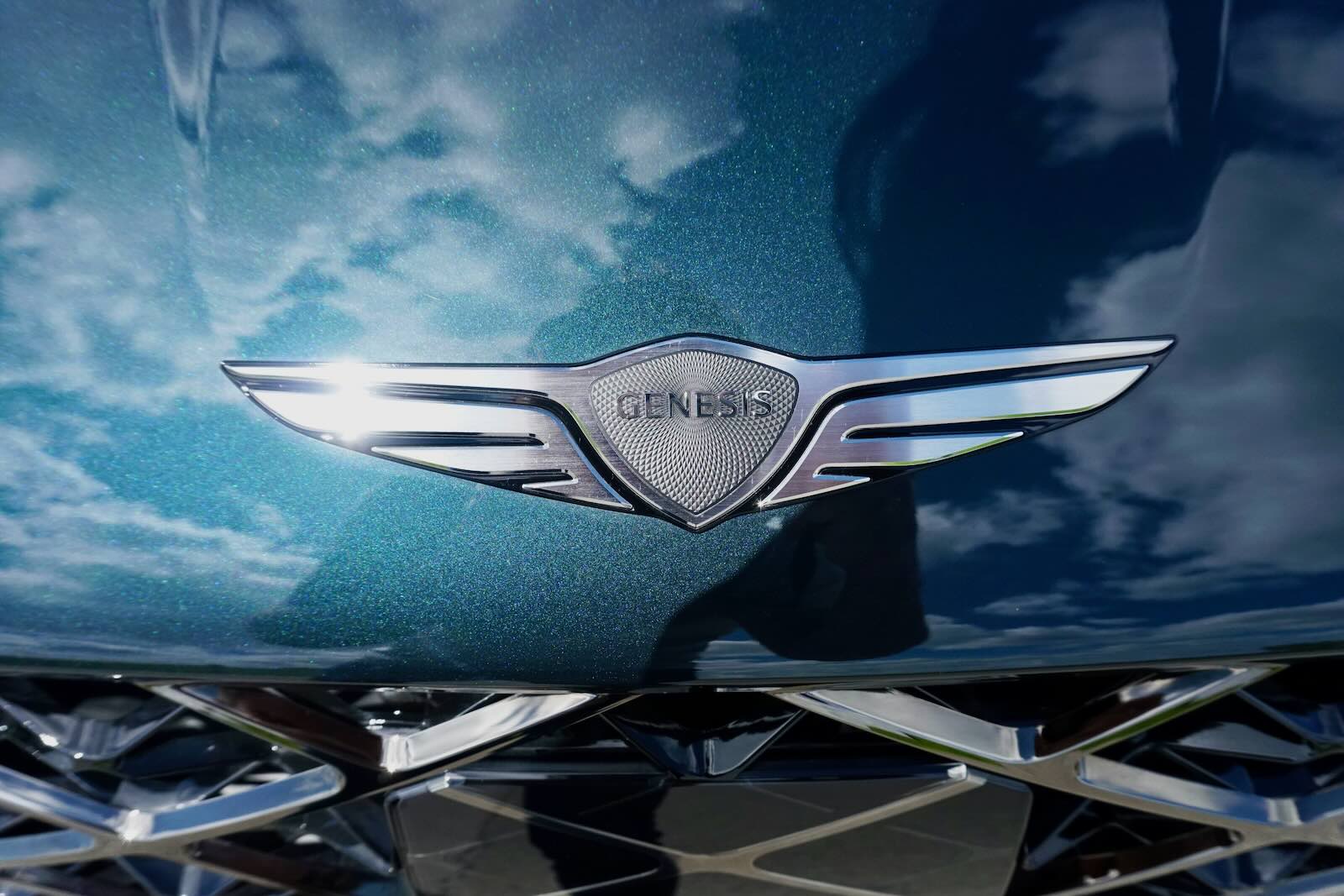 Closeup of the Genesis logo on the hood of a G80 luxury sedan.