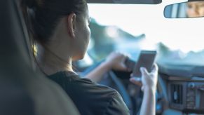 A teenage driver behind the wheel with cell phone in-hand.
