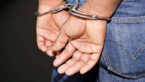 Closeup of the handcuffed hands of a person arrested on an airplane.