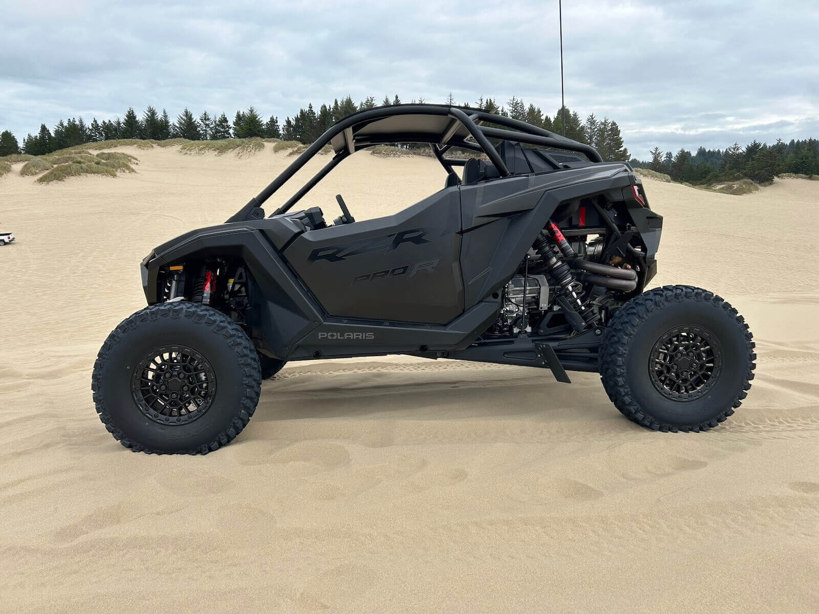 A black Polaris RZR Pro R on the sand after some off-road driving. 
