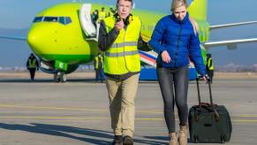 Airport manager leading a detained woman away from an airplane.
