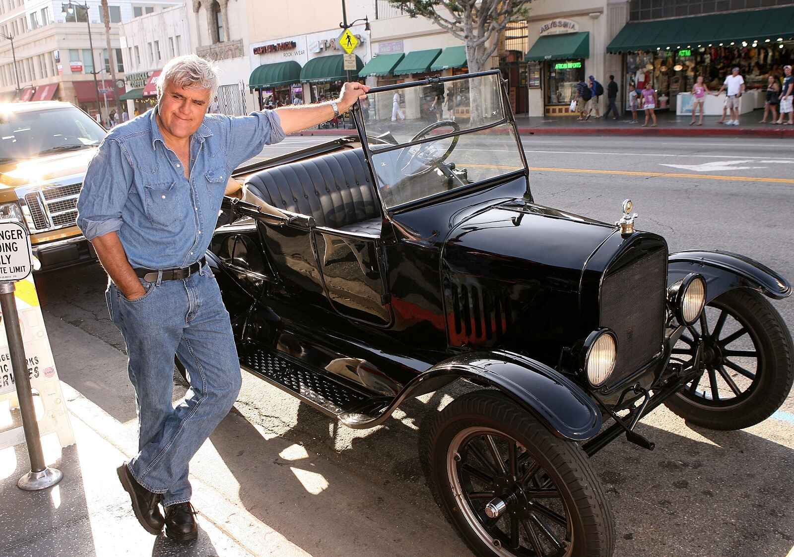 Jay Leno stands next to a black vintage vehicle part of his car collection in Los Angeles, 2009