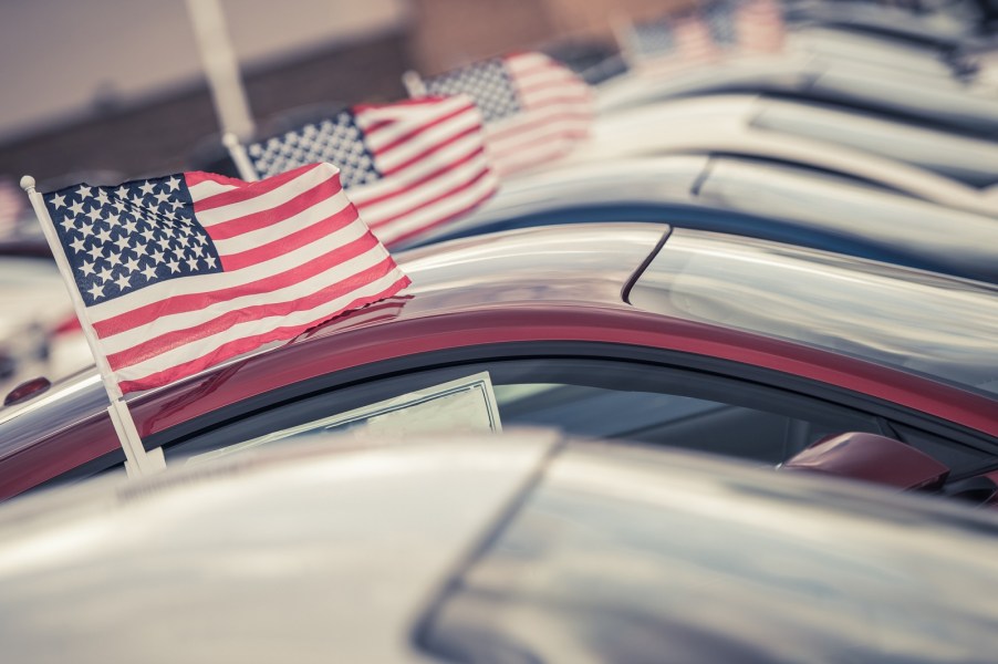 A row of cars in very close view with American flags in the windows parked at a car dealership